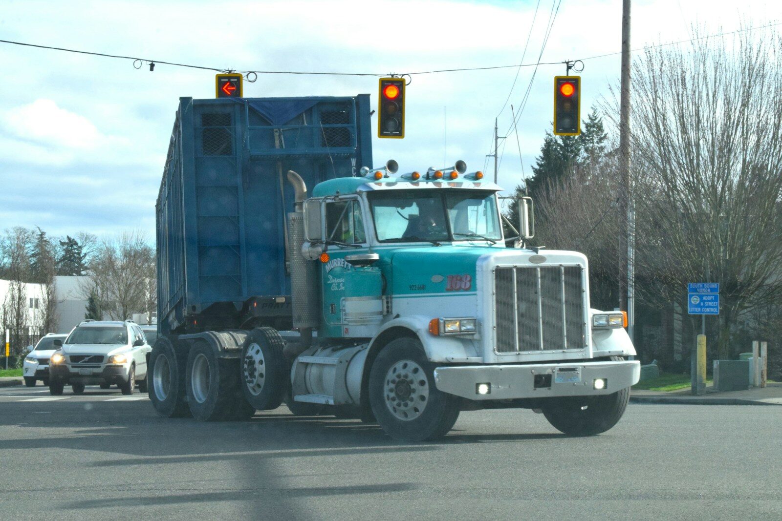 a blue dump truck driving down a street